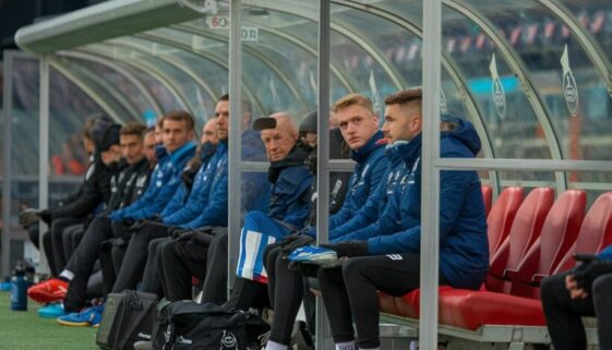 Ersatzbank mit Spielern und Betreuern hinter Plexiglas im Fußballstadion