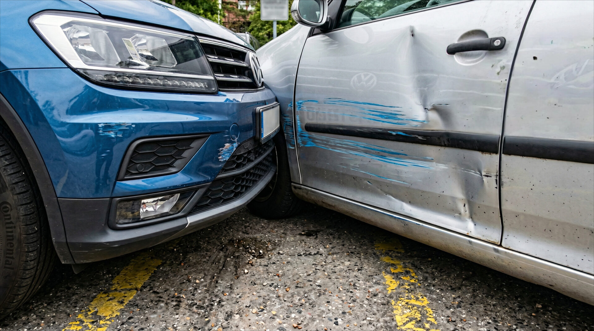 Nahaufnahme zweier Autos auf einem Parkplatz: Blaue Lackspuren an einer silbernen Tür passen zur Höhe der blauen Stoßstange.