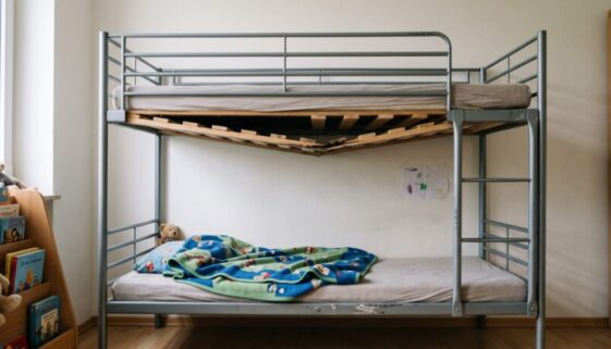Verrutschte, lose Bettkonstruktion im oberen Teil eines Metall-Etagenbetts in einem ruhigen Betreuungszimmer mit deutlich sic
